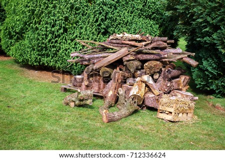 Logs, sraw and firewood stacked together already chopped and ready for the fireplace or bonfire on the green grass