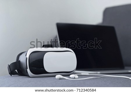 VR headset with earphone and laptop on sofa in living room background, innovation technology concept

