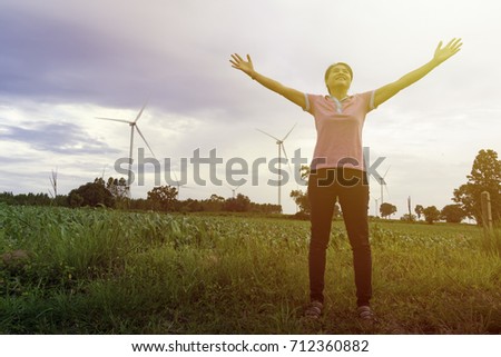 Young woman raise hands up for her success in sunset wild turbine field background, Concept of Success in life.