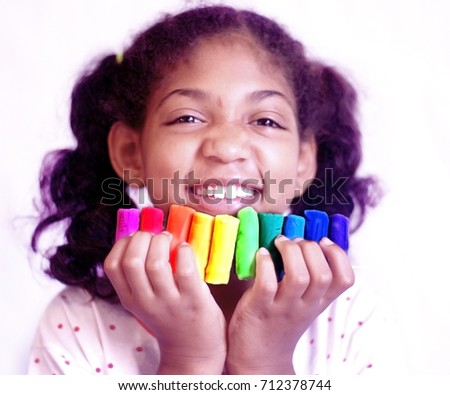 Little girl holds in her hands the dough elements of all colors to make multicolored object models