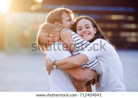 Portrait of a young united family. Father keeps a small daughter in his arms. Woman gently embraces husband and daughter. Royalty-Free Stock Photo #712404841