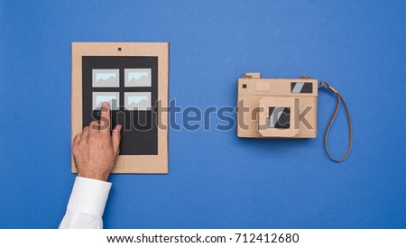 User viewing pictures on a cardboard tablet and handmade camera, crafts and creativity concept