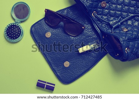 What do women store in their bags? Stylish women's accessories and cosmetics lie on a green background.