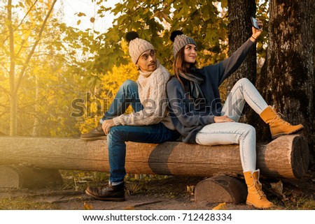 Young and happy couple sitting on the bench in autumn park