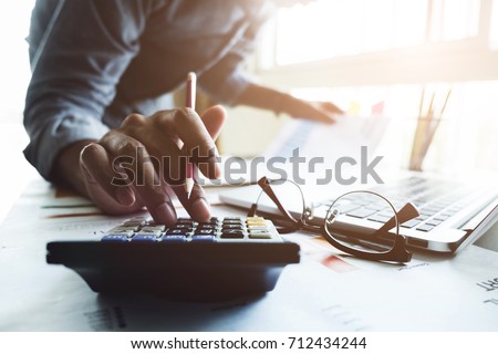 Close up of businessman or accountant hand holding pen working on calculator to calculate business data, accountancy document and laptop computer at office, business concept Royalty-Free Stock Photo #712434244