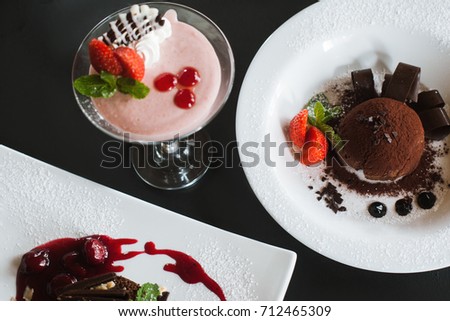 Presentation of delicious desserts in restaurant. Creamy strawberry souffle and chocolate fondant decorated sweet red berries and mint, close up picture