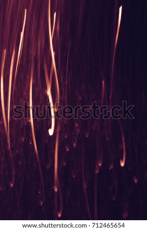 Abstract background of yellow lines in motion on black. Bokeh of defocused vertical curves, blurred neon leds of serpentine, festive backdrop of holidays, fireworks and celebrations
