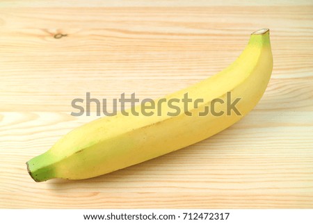 One Ripe Banana Isolated on Natural Wooden Background, with Free Space for Text and Design 