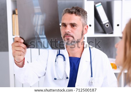 Mature male doctor hold in arm and look at xray photography discussing it with female patient portrait. Bone disease exam, medic assistance, cancer test, healthy lifestyle, hospital practice concept