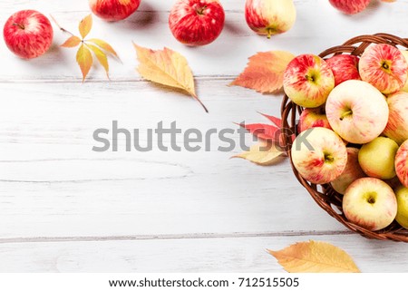 autumn mood composition with red apples in wicker basket and yellow leaves