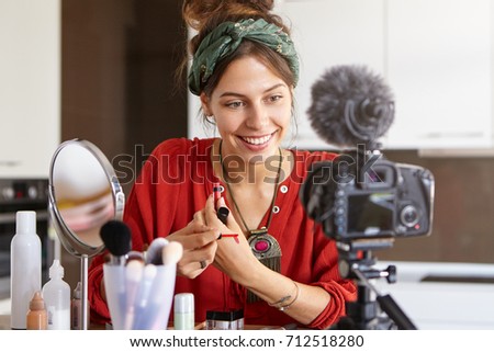 Attractive woman beauty fashion blogger recording content for blog, trying out new lip gloss on her wrist. Pretty girl vlogger swatching lipstick while making video review of cosmetics products