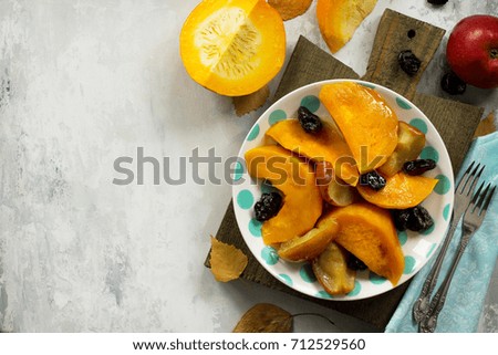 Pumpkin baked with apples, prunes and spices in a bowl on a stone background. Flat flay, top view with copy space.