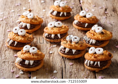 Heloween dessert: funny monsters made of biscuits with chocolate and marshmelow close-up on the table. horizontal
