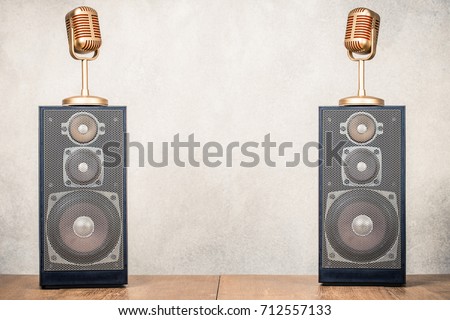 Retro old stereo acoustic speakers system and golden microphones front concrete wall background. Listening music concept. Vintage instagram style filtered photo