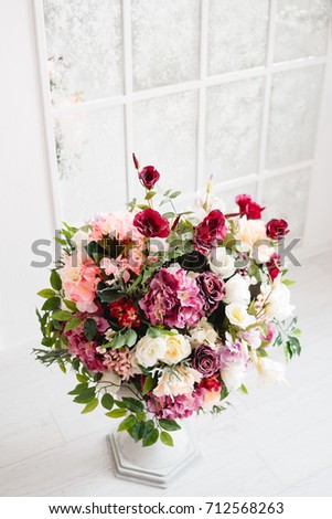 Magnificent bouquet of flowers in white vase. Indoor decoration, gallery, photo studios. Beautiful cream and dark-violet roses, deep red eustoma, purple hydrangea, free space