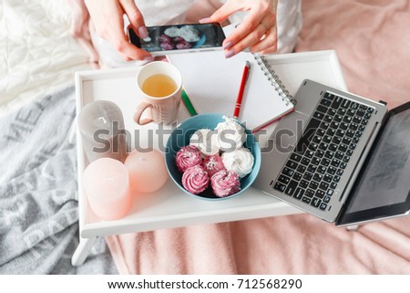 Unrecognizable woman makes photo of sweets by smartphone. Food photography of zephyrs during process of breakfast and working, social media, close up top view