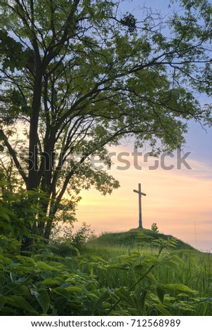 Cross on a hill during sunset. It is surrounded by acacia trees.
