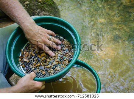 Gold panning and gem mining.  Prospecting tool of classifier used to sift and sort material. Classify mineral rich soil, dirt, pebbles and stones. Prepare soil to pan. Fun, adventure and recreation. Royalty-Free Stock Photo #712581325