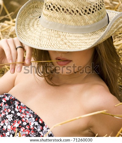 Beauty cowgirl relaxing in the straw in field