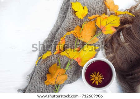 Yellow autumn leaf cup of tea hair on a white wooden background