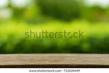 Empty wood table top on blur abstract green from garden