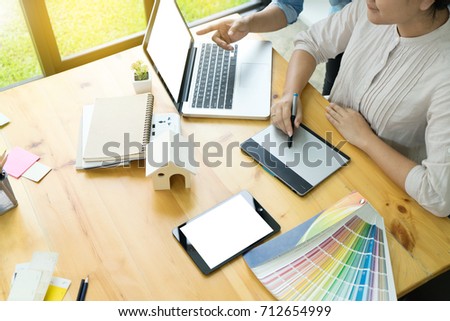 Team work for graphic design working on wood table with computer tablet electronic pen and color chart, white computer screen and tablet screen with clipping path.