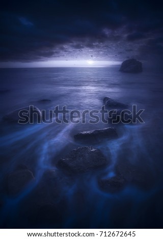 Beautiful moonrise over the sea with unusual waves on a beach. Night landscape.