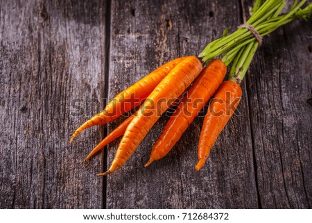 Young carrots with a tops on a wooden background, horizontally