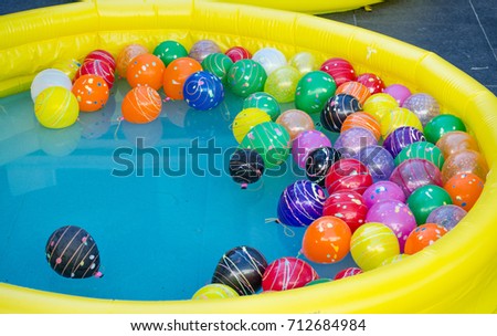 Yellow Rubber pool with colorful balls in the water.