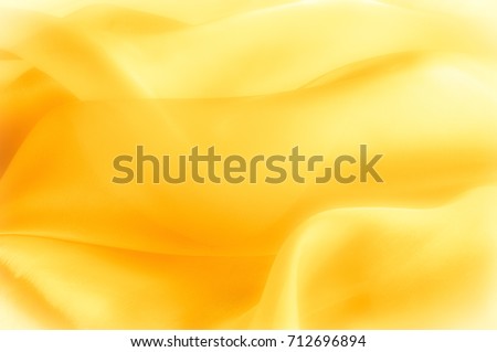 The photo is blurred. Texture, background, pattern. Yellow silk fabric. Abstract background of luxury Yellow fabric or liquid wave or wavy grunge texture. The whole background. Royalty-Free Stock Photo #712696894