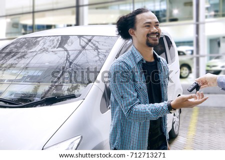 Picture of an African man getting a car key while standing near his new car in the showroom