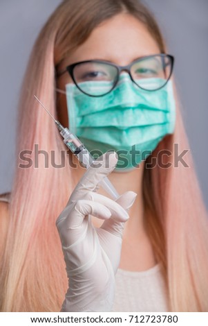 Young pretty nurse with syringe needle isolated on grey background