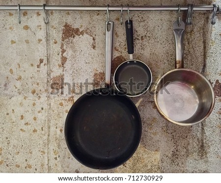 Frying Pan Two Size and Stockpot on Grunge Cement Wall (Little Space for Text Beside) Royalty-Free Stock Photo #712730929