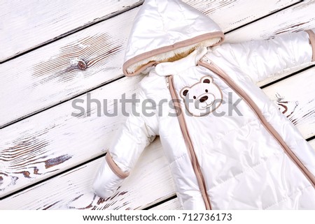 Baby white warm winter romper. Kids high quality winter bodysuit on white wooden background.