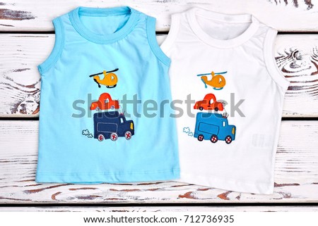 Set of colored printed t-shirts for kids. Baby boy new collection of high quality cartoon t-shirts, old wooden bakground, top view.