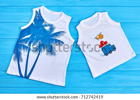 Boys and girls trendy t-shirts. Organic printed kids t-shirts, blue wooden background. Cotton patterned childrens summer apparel.