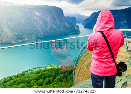 Tourism and travel. Woman tourist nature photographer taking photo with camera, enjoying Aurland fjord landscape from Stegastein lookout, Norway Scandinavia.