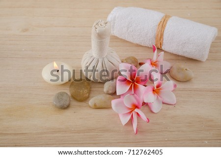 Pink frangipani flowers with herbal ball ,pile of stones ,towel on light wooden board 