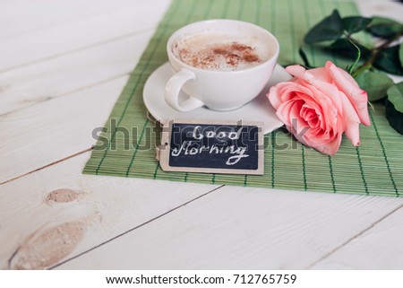 Coffee mug with rose nd notes good morning on white rustic table from above, tasty breakfast, vintage toned