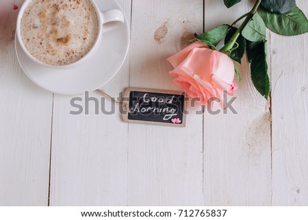 Coffee mug with cake ,rose and notes good morning on white rustic table from above, tasty breakfast