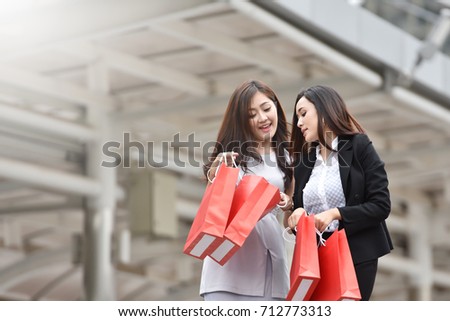 Happiness Asian women with red shopping bags over Office building background in the City. Copy space.