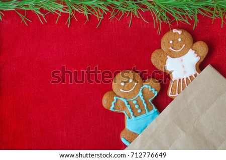 Christmas gingerbread mans on red velvet background. Boy and girl peer out of the package. Concept of new year gift. Picture for a confectionery catalog. Invitation or greeting card with copy space.