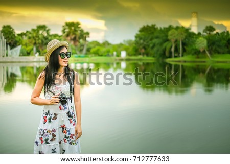 Asian woman photographer taking photo beside the marsh.Asia tourist standing near the pond for her vacation.