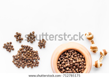 pet care with dry food for pet - dog in plastic bowl and paw on white background top view space for text