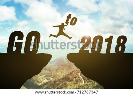 Silhouette of business man jump to 2018 text. keep go on to success concept at 2018 over a beautiful high view mountain background. success in 2018 years. GO TO 2018 YEAR CONCEPT