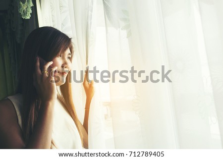 Beautiful young woman talking by telephone indoors.