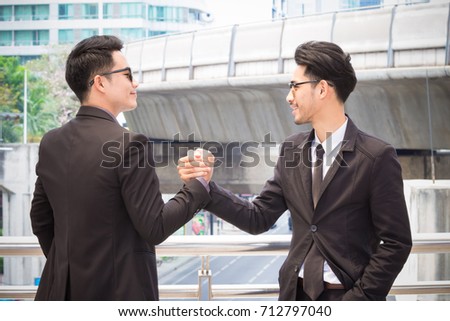 Two smart businessmen are wrestling hands  closing a deal with smiling face. Business partners who have a good relationship to each other.