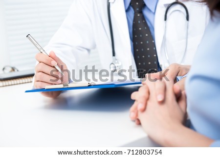 Male doctor noting a female patient medical check up information in hospital Royalty-Free Stock Photo #712803754