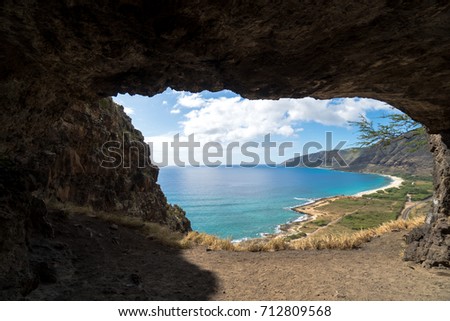 Stunning view of the mountains and oceans with a road going away from the photographer. Blue skies up above with puffy clouds, yellow grass. High view from the cave looking out into the ocean.