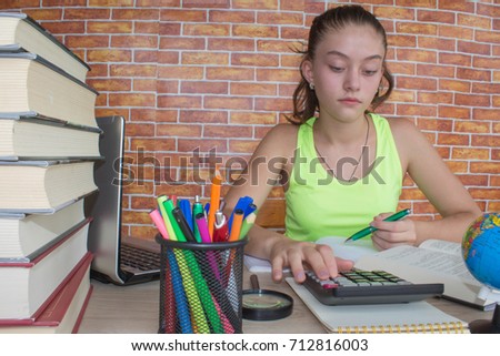 Young girl student sitting between books and calculate. Student, Young Girl with bills and calculator in the room at home